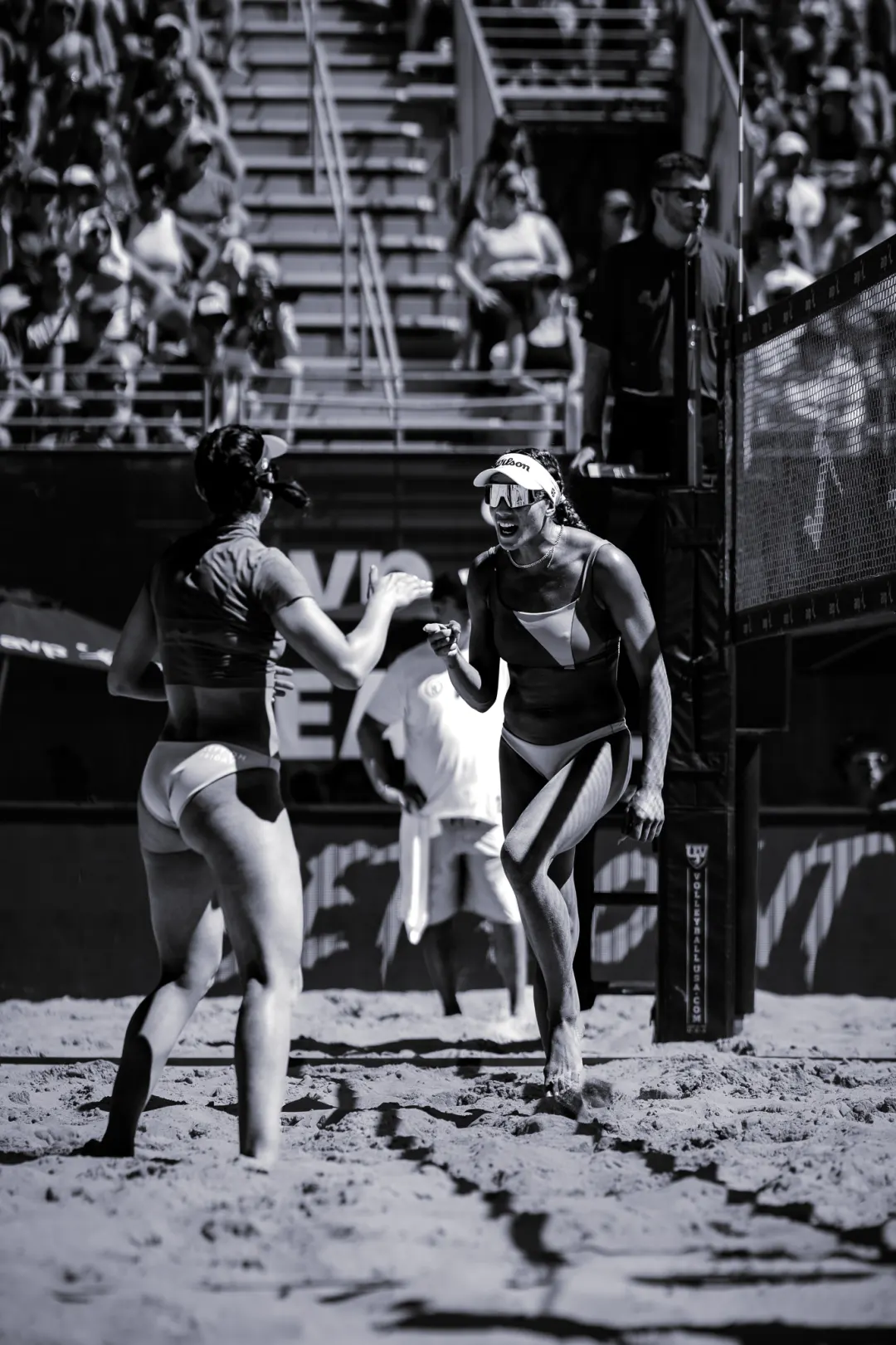 Beach volleyball players celebrating at the net