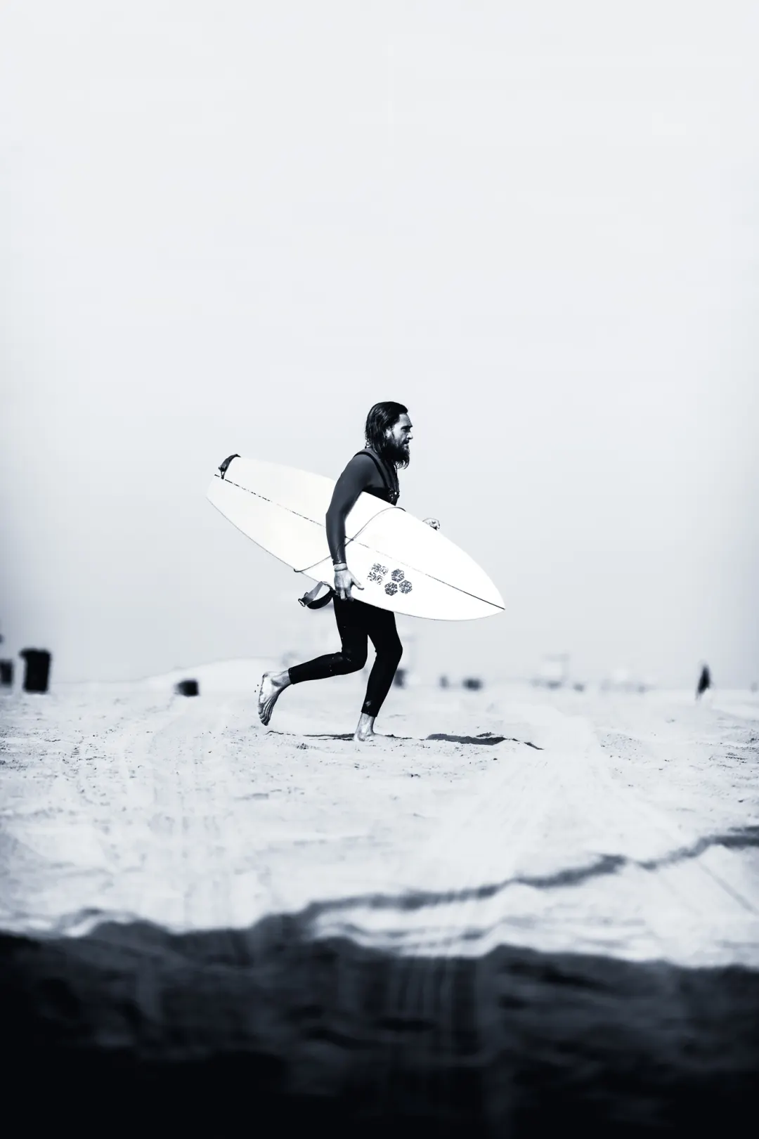 Surfer carrying a board through bright ocean spray