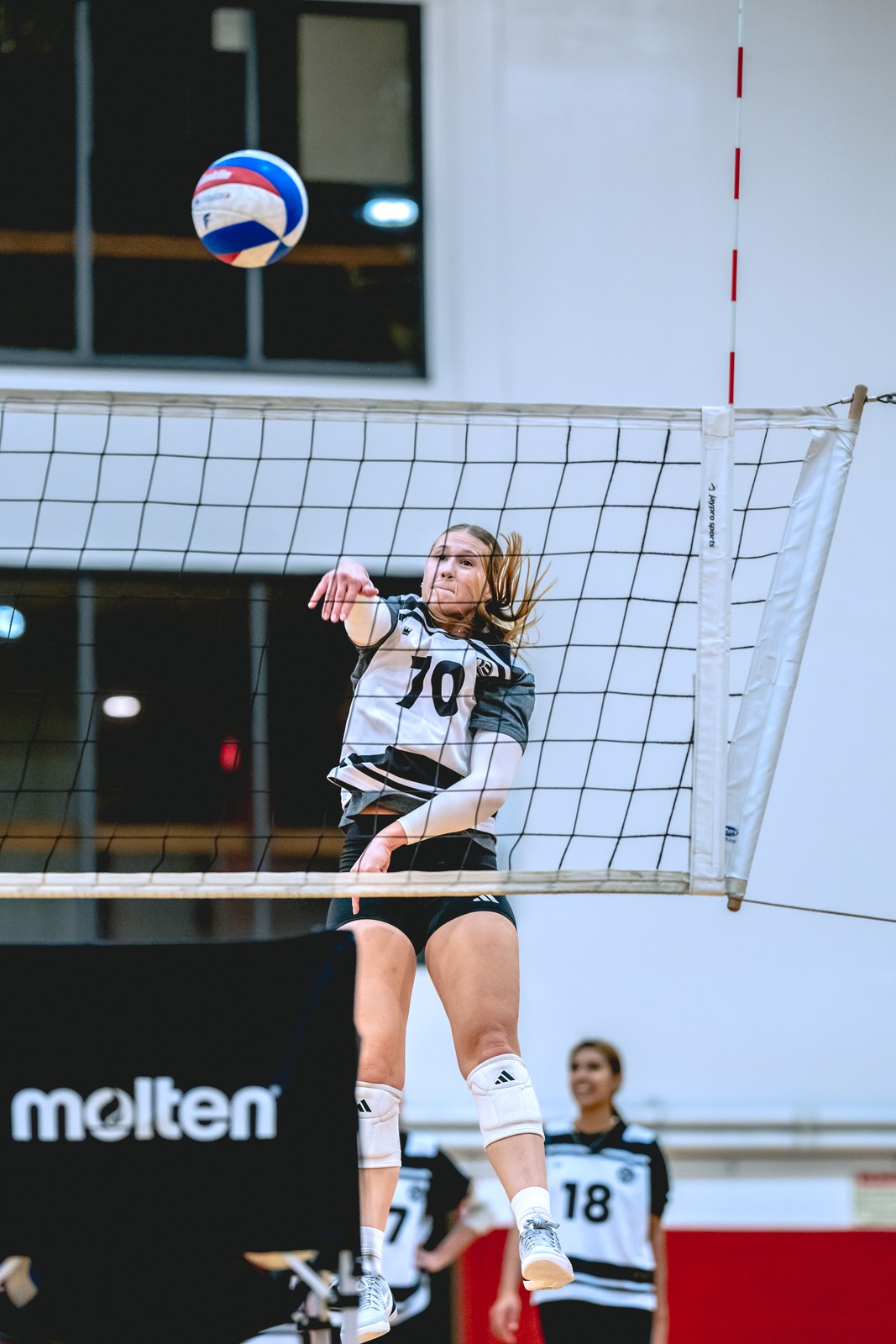 A player in a white and gray uniform reaches for the ball.