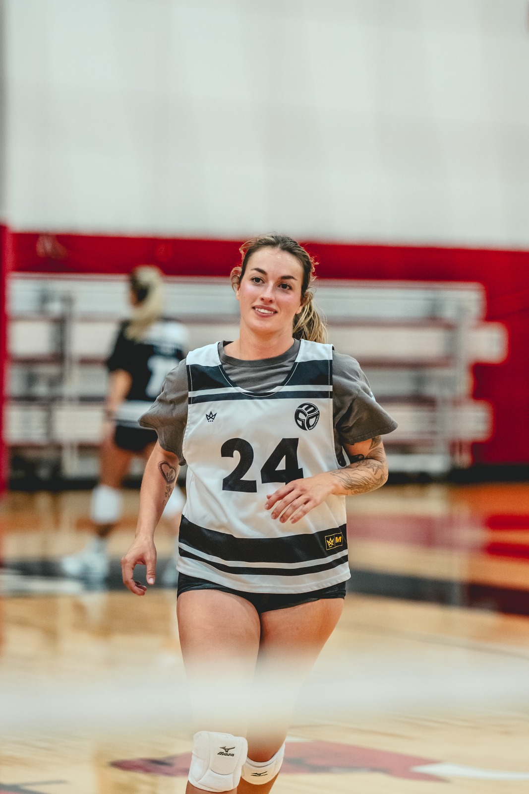 A player in a white and black jersey smiles on a court.