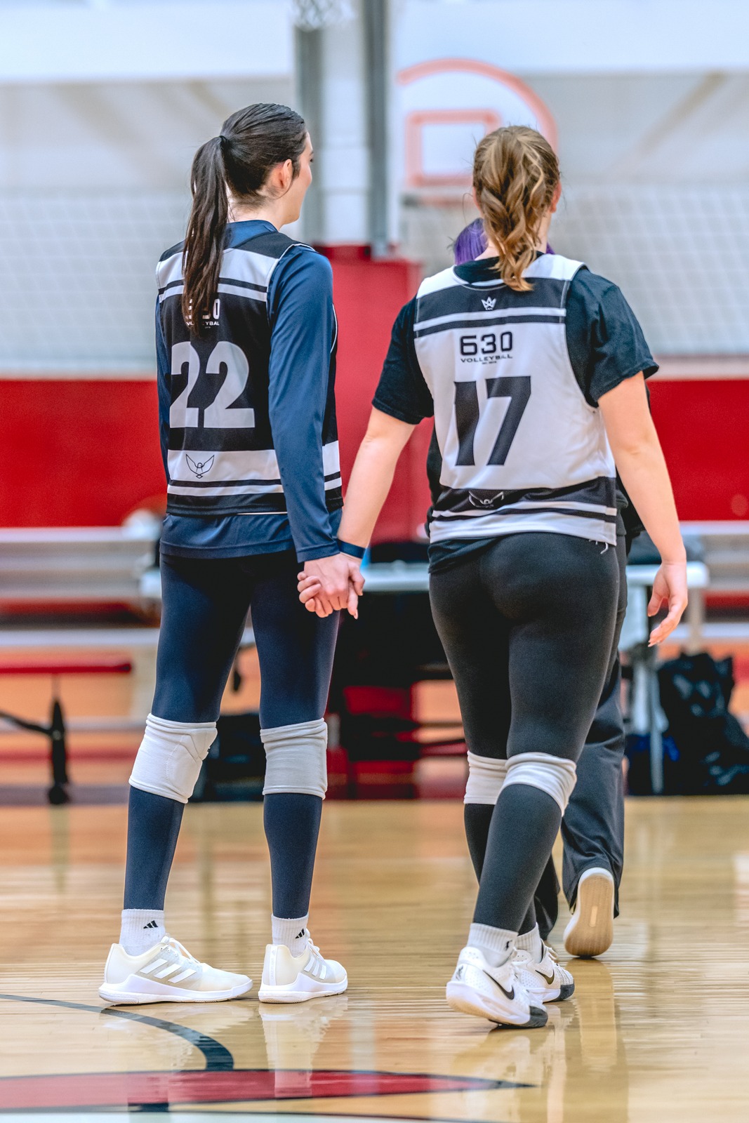 Two players walk on a court, holding hands.