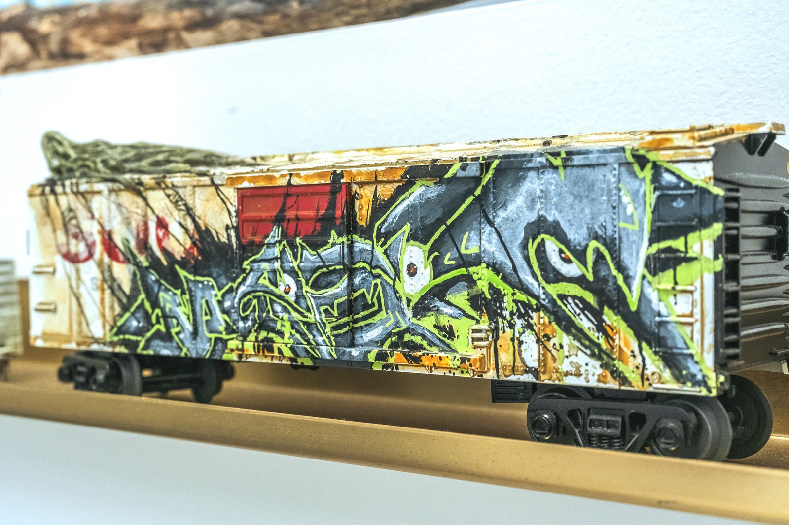 A model train car is covered in colorful graffiti art.