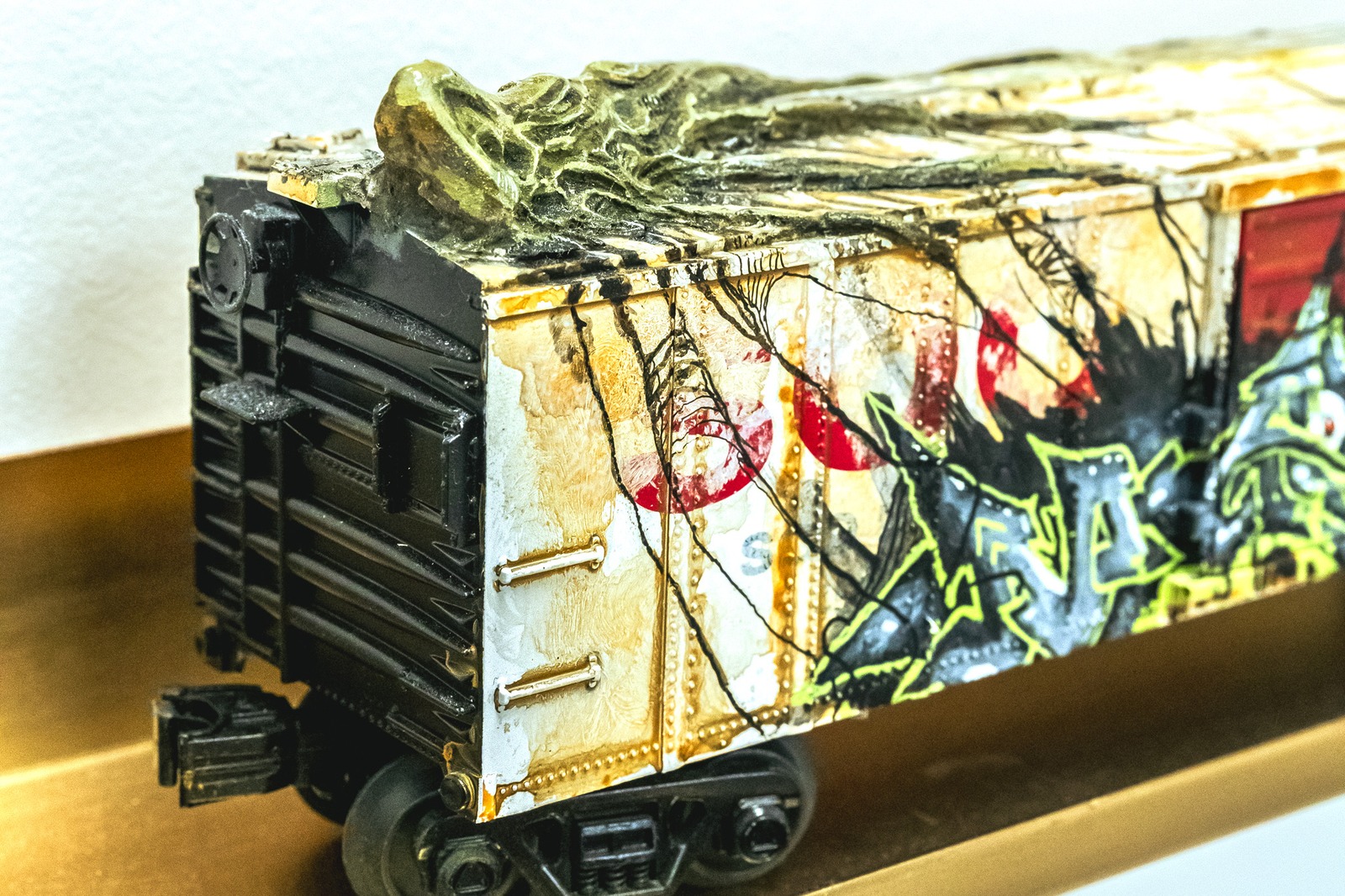 A miniature train car is covered in graffiti and a textured, rocky overlay.