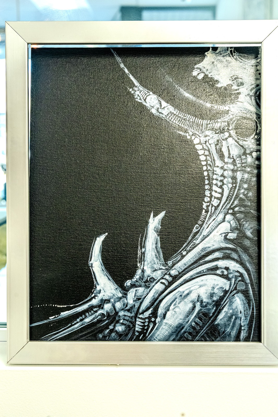 A framed painting depicts a creature with intricate, metallic-like structures.