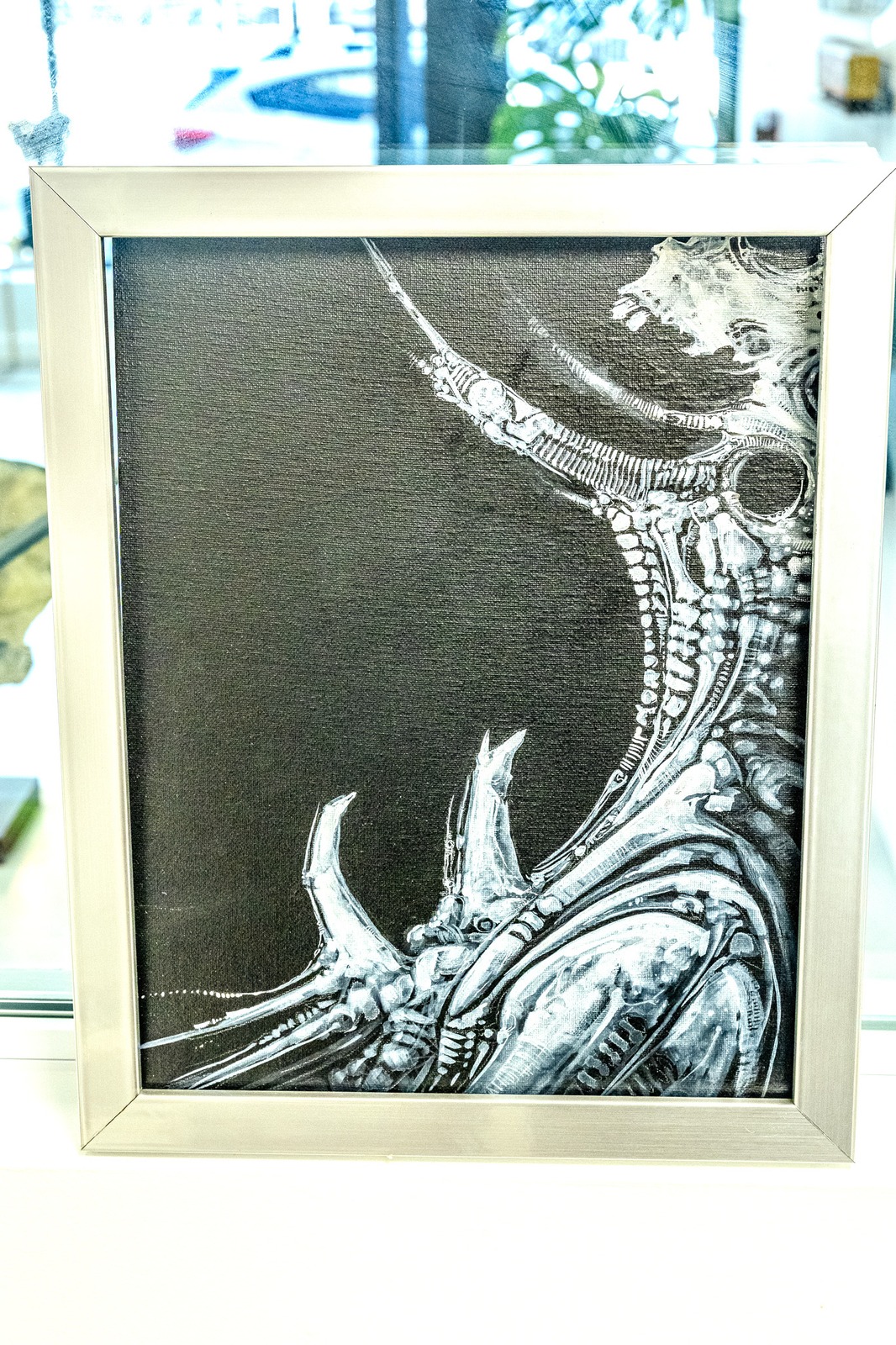 A framed black and white artwork depicts a creature's head and neck.