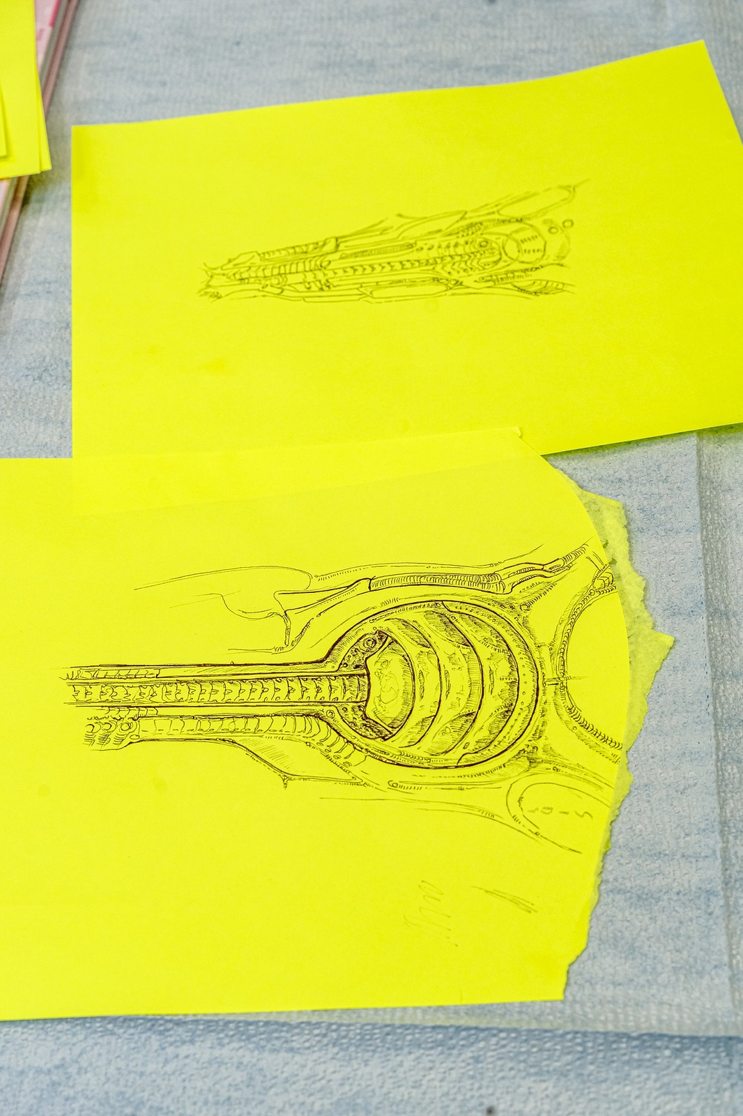 Two sketches of mechanical designs on yellow paper.