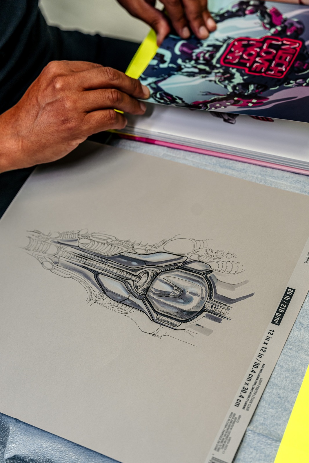 A person in a black shirt turns pages of a book with colorful artwork.