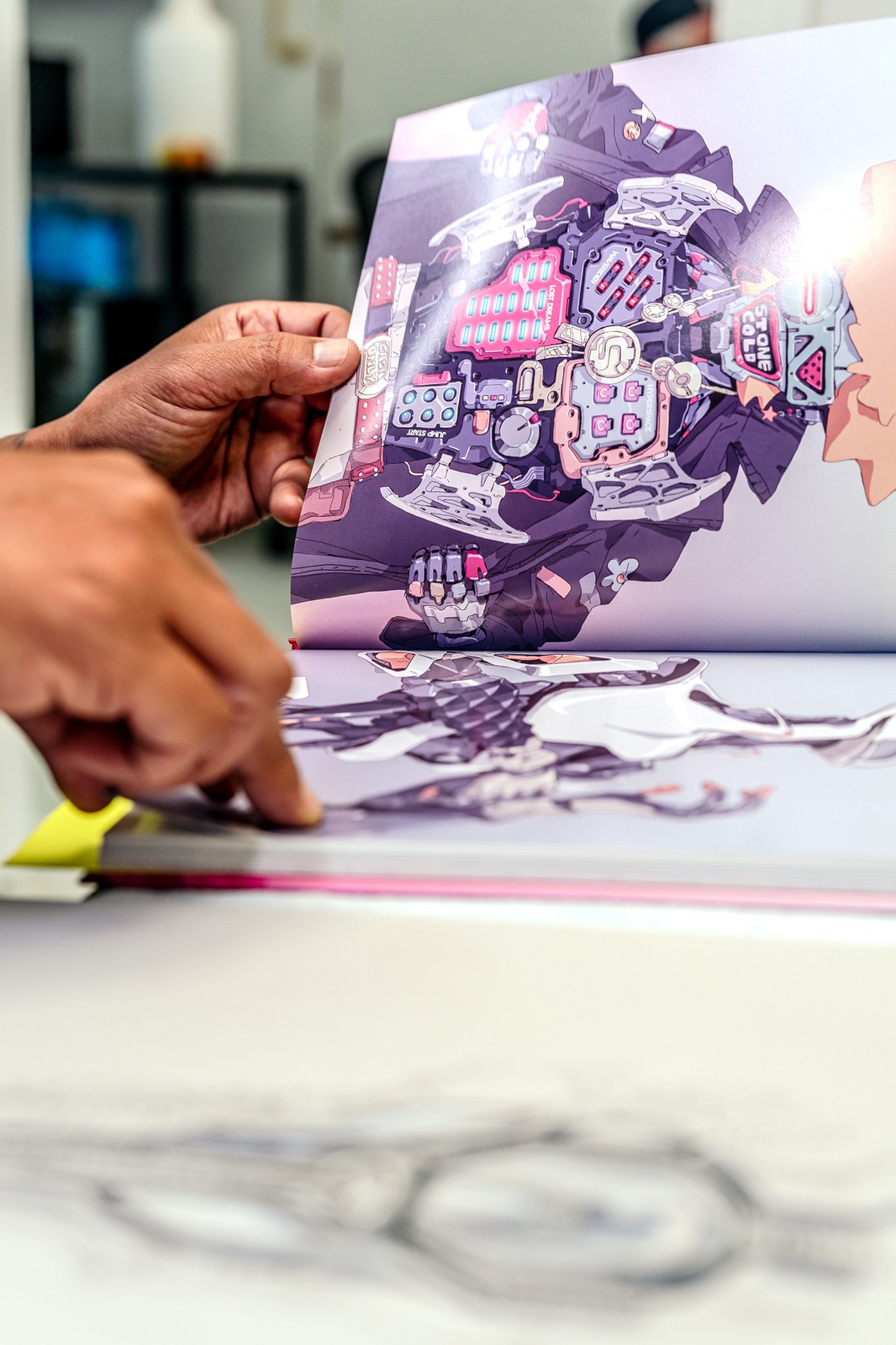 Hands turn the pages of a book with intricate illustrations.