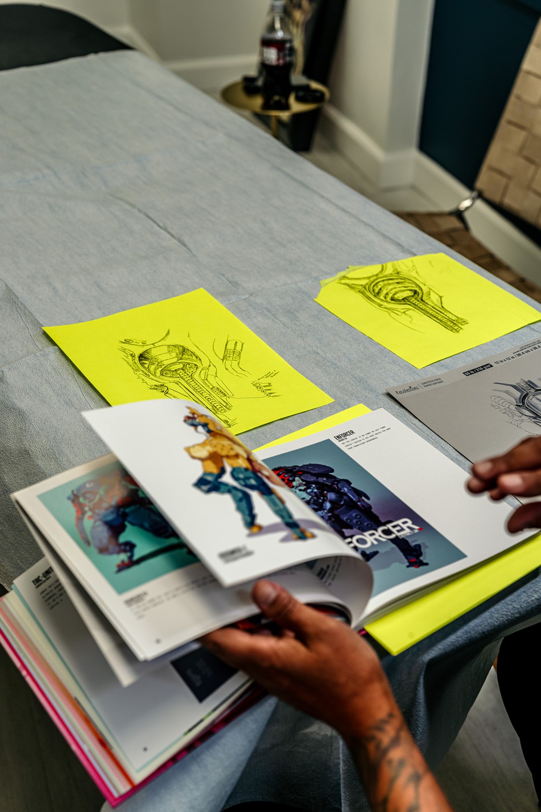 A person holds an open portfolio with character art visible.
