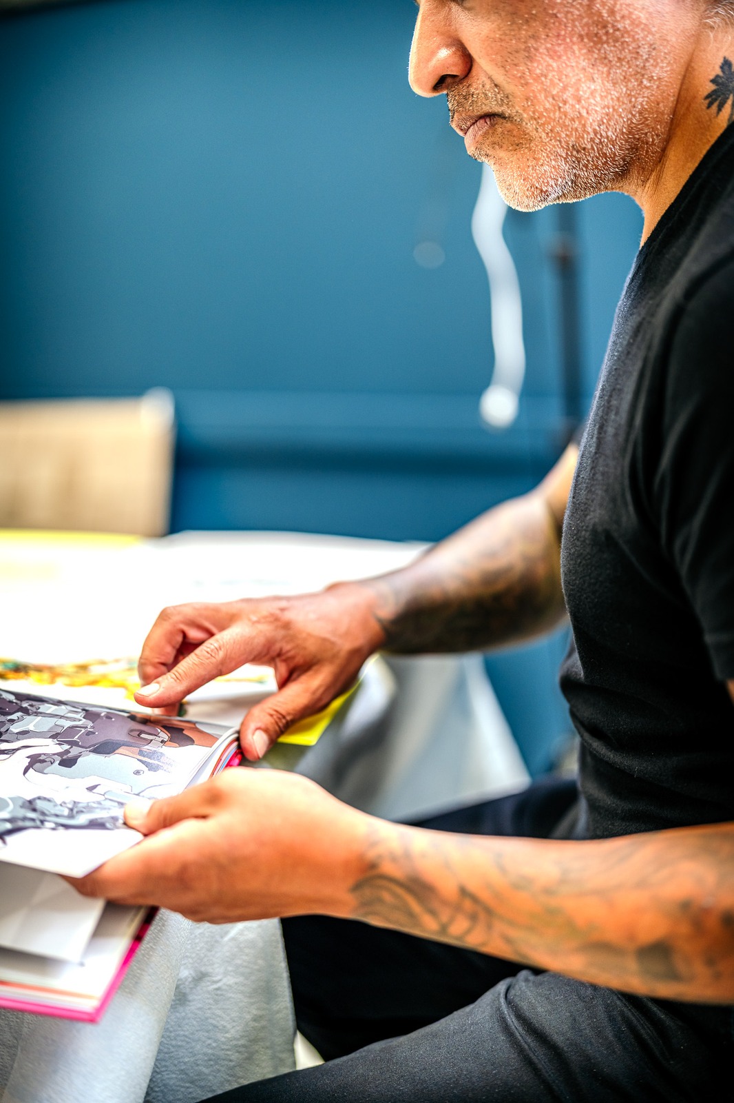 A person in a black shirt looks down at a book.