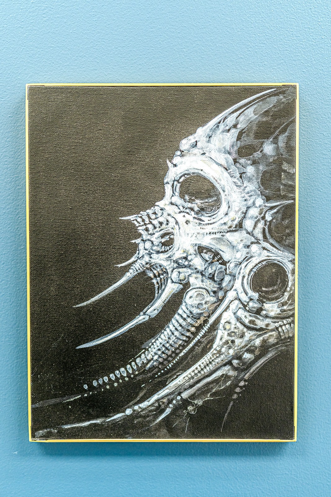 A painting of a creature with sharp teeth and metallic elements on a black background.