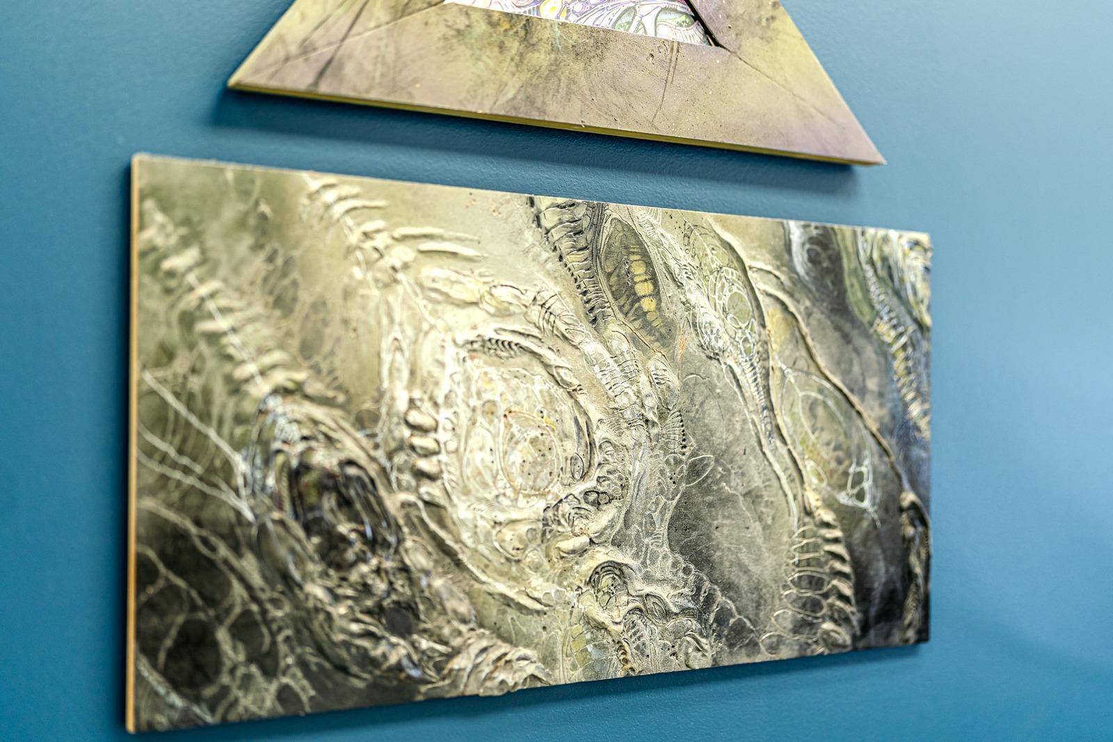 Close-up of textured artwork on a blue wall.