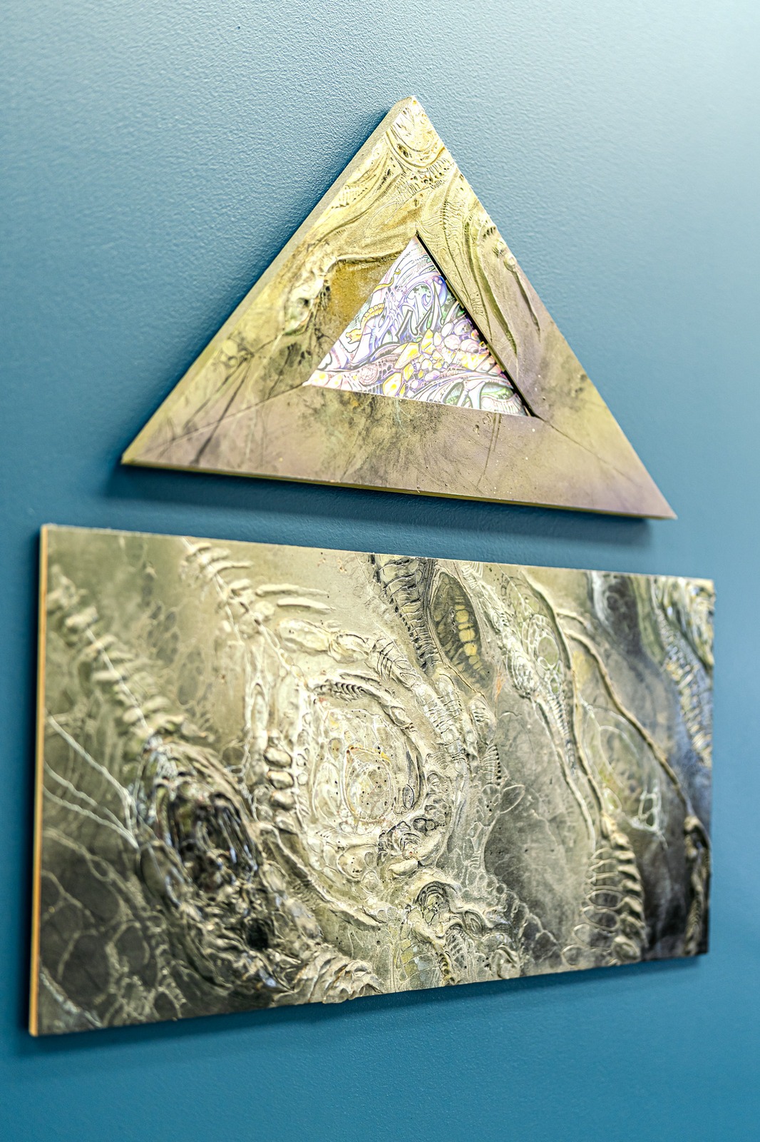 Two framed artworks hang on a teal wall.