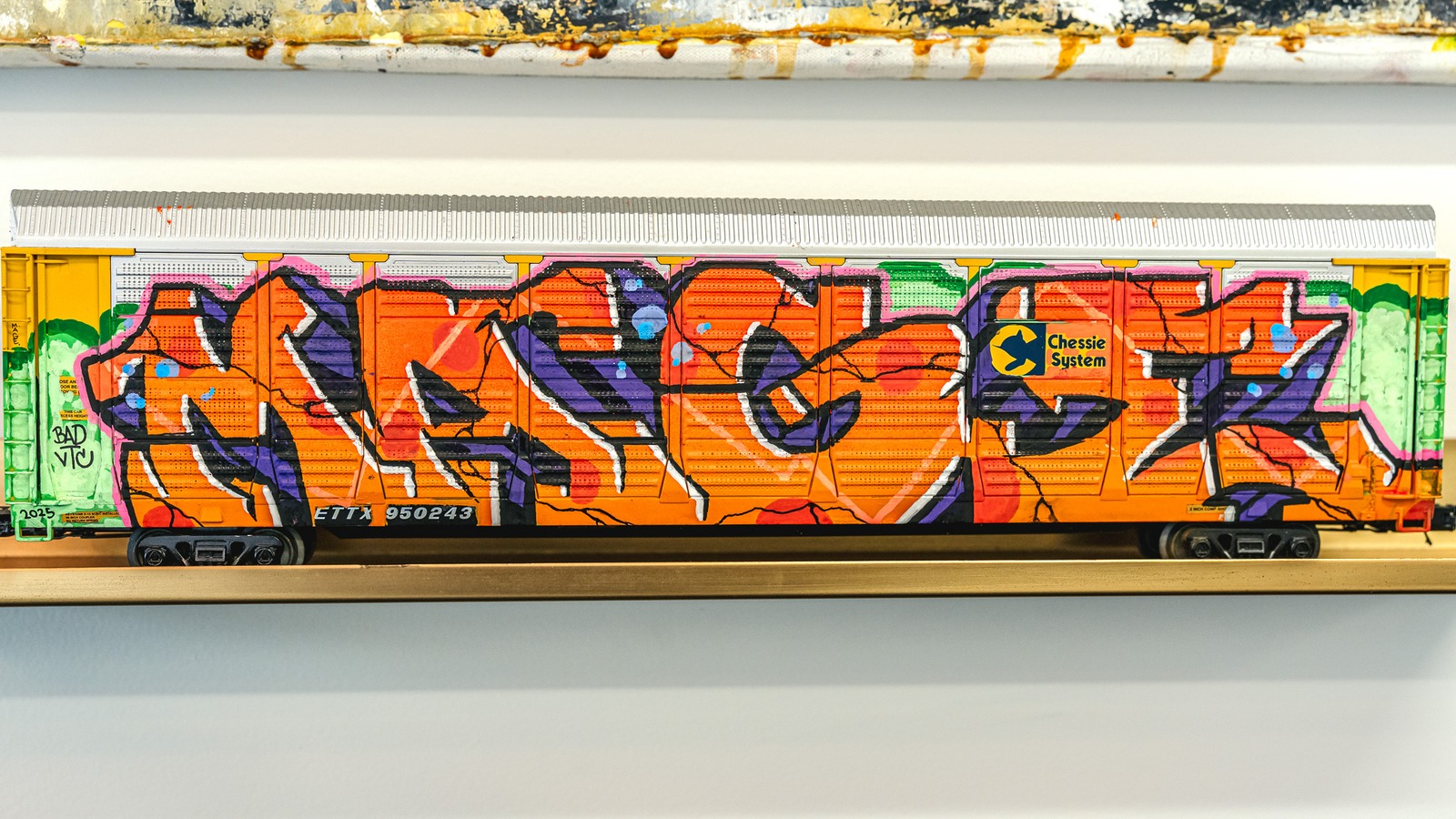 A model train car is covered in colorful graffiti.