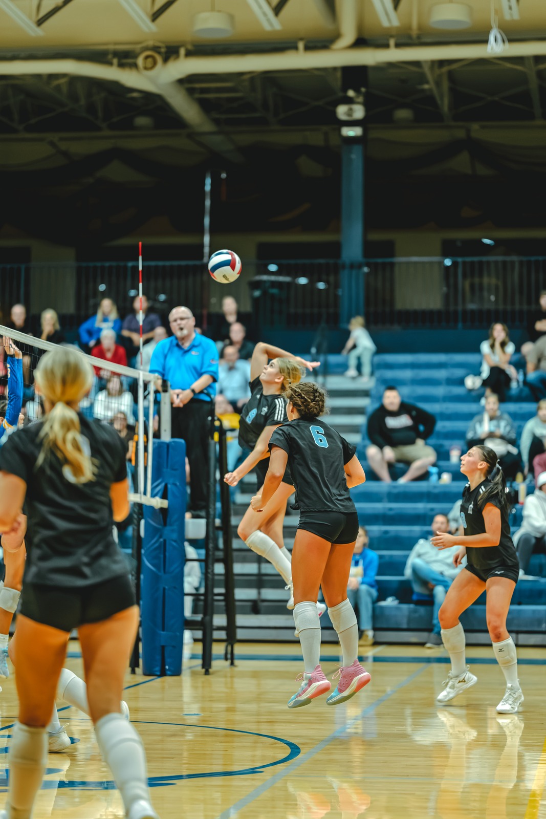 A player in black jumps and reaches for the ball.