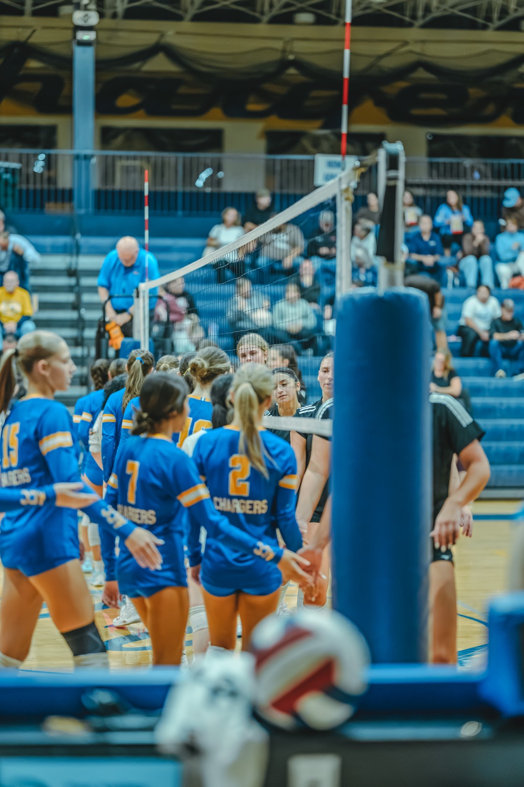 A player in blue reaches for the ball near the net.
