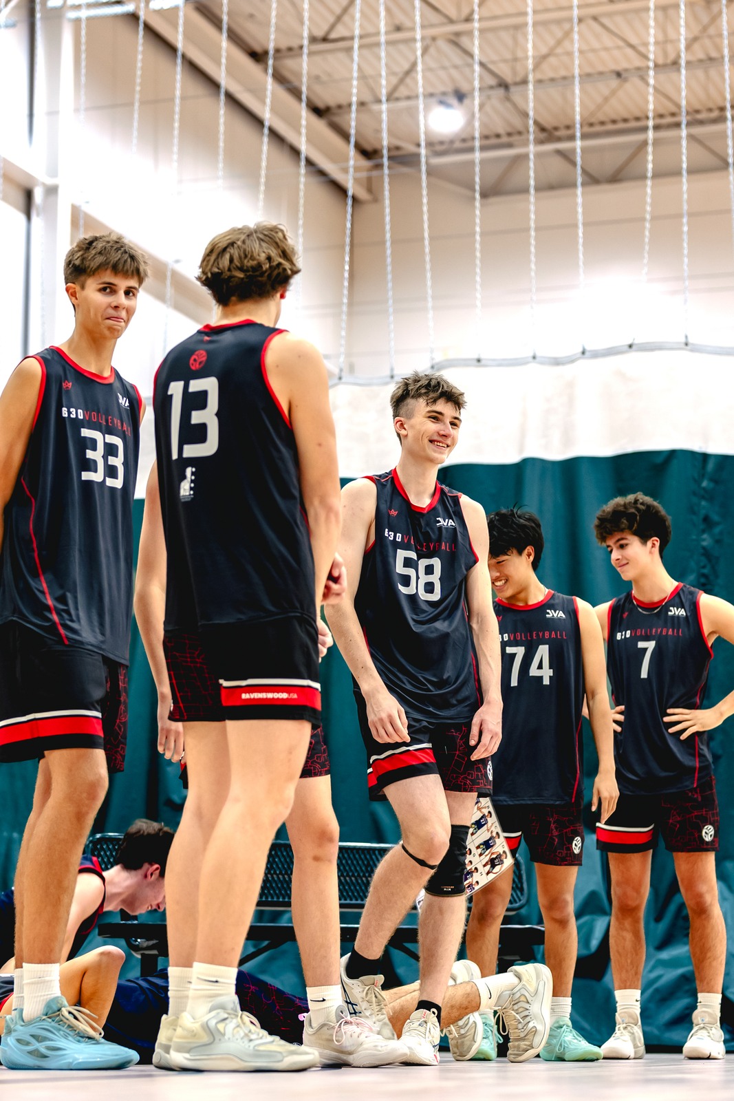 A group of players in black and red uniforms stand on a court.