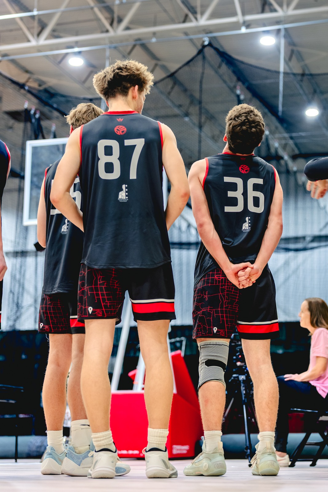 Players in black uniforms stand with hands behind their backs.