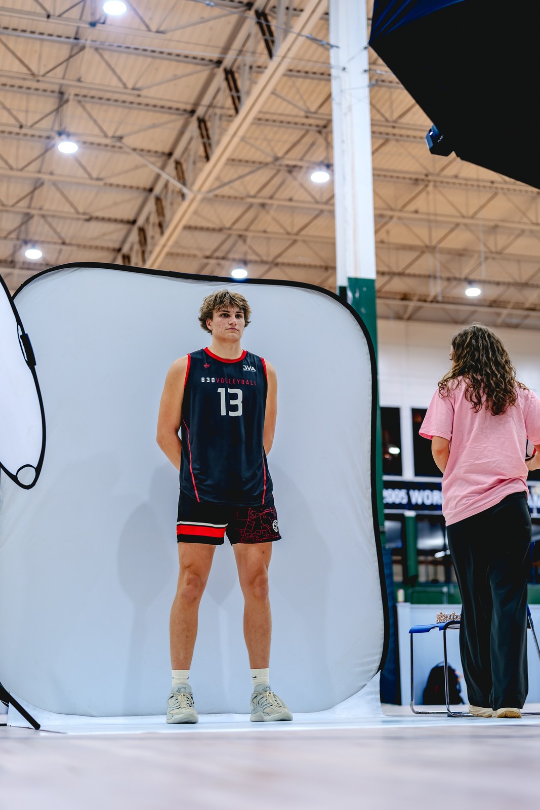 A player in a black jersey stands with hands behind their back.