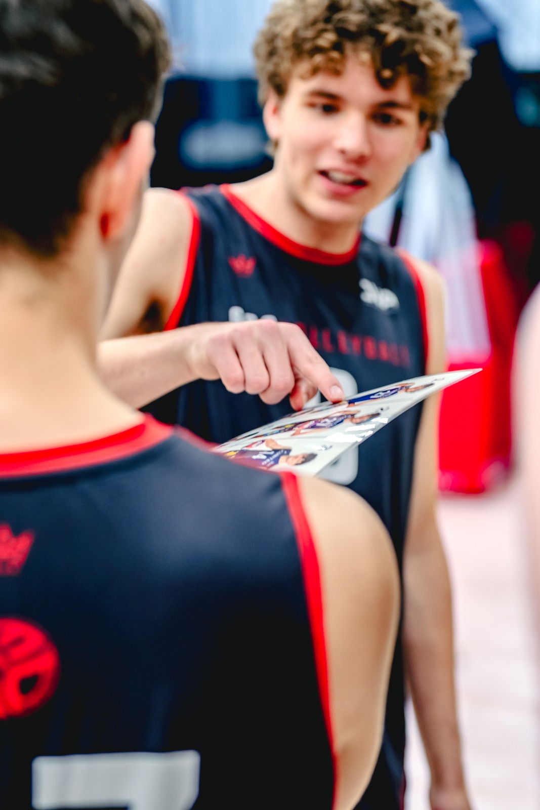 A player in a black top points at a card held by another player in a black top.