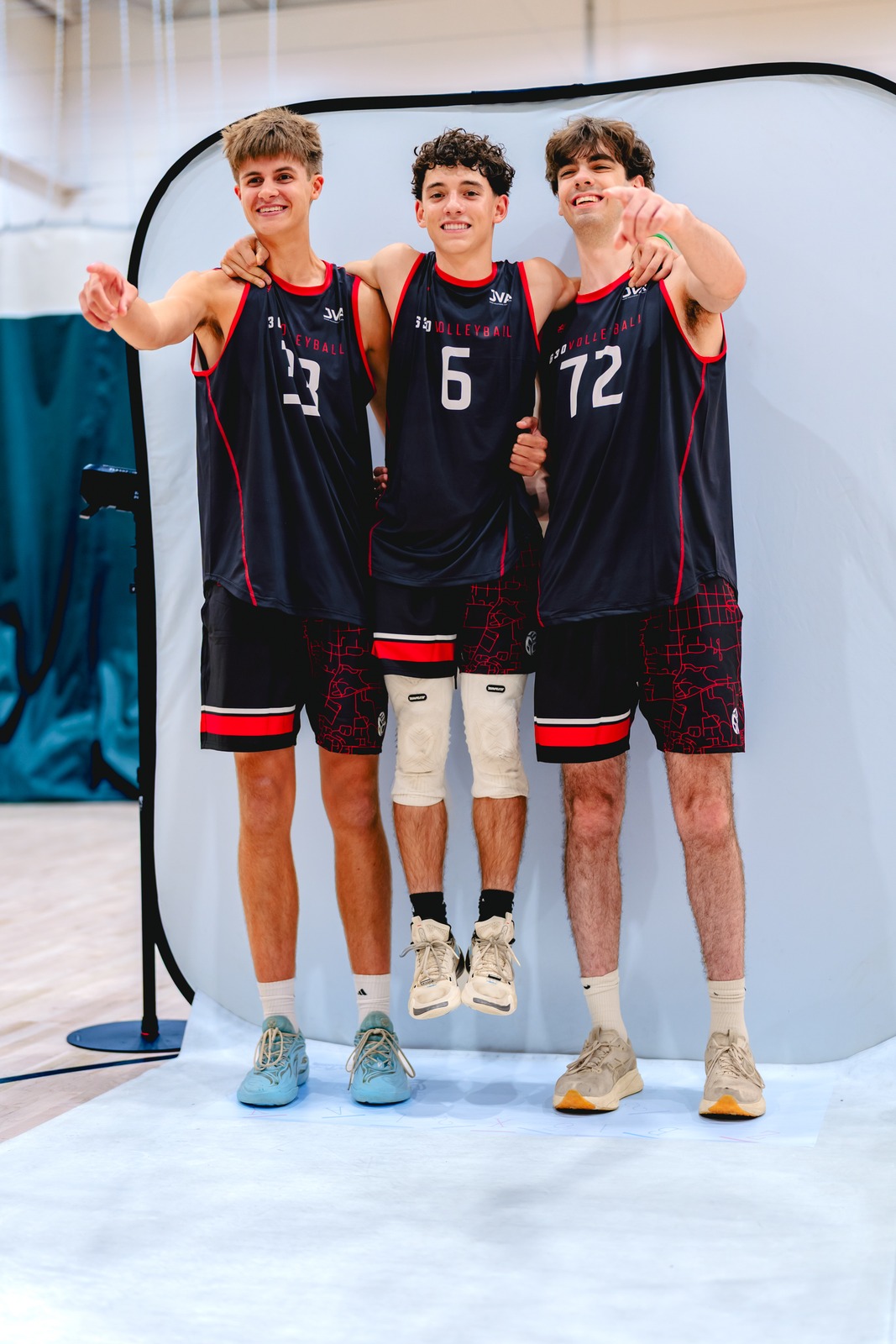 Three players in black jerseys stand together, with arms around each other.