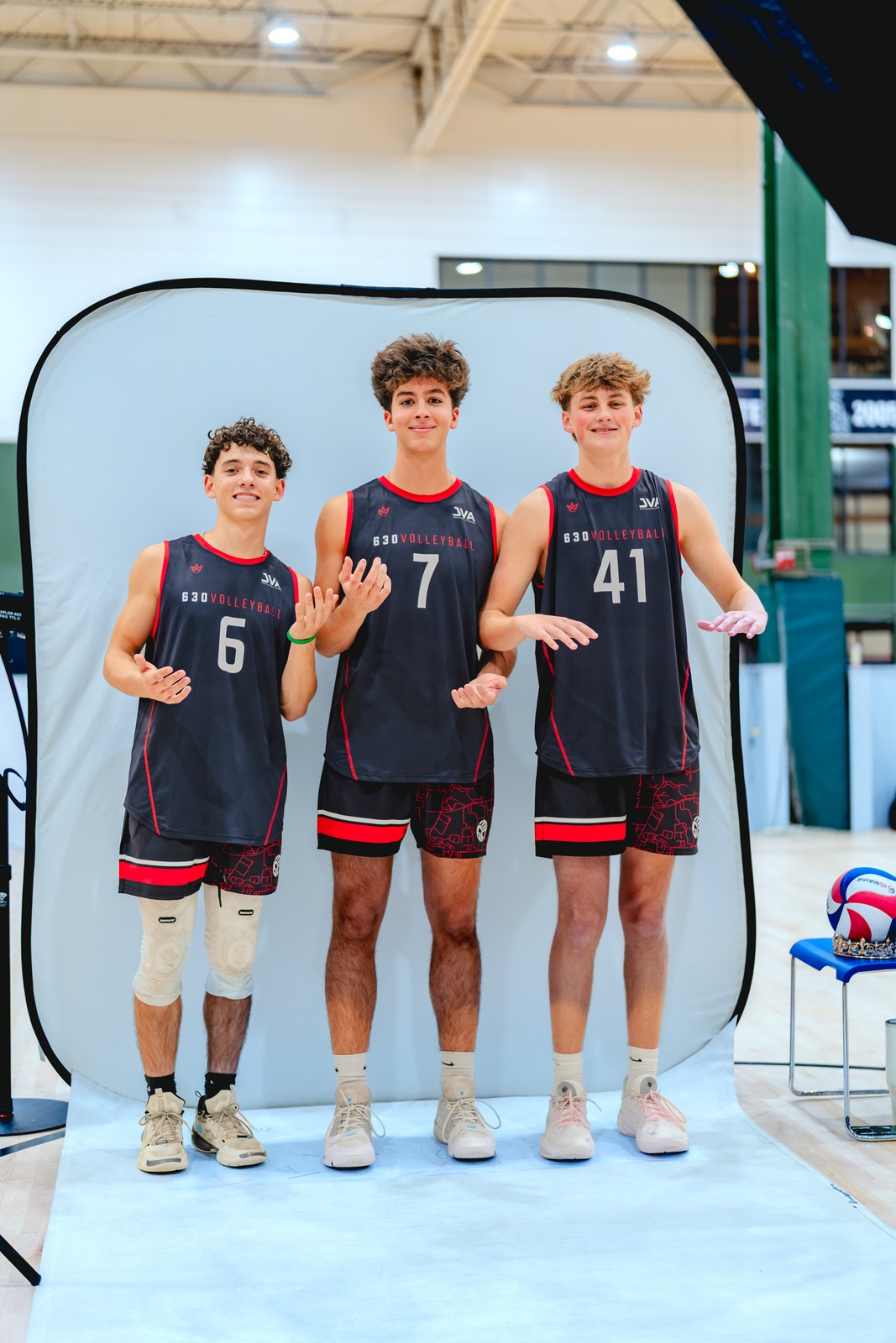 Three players in black and red uniforms stand with open hands.