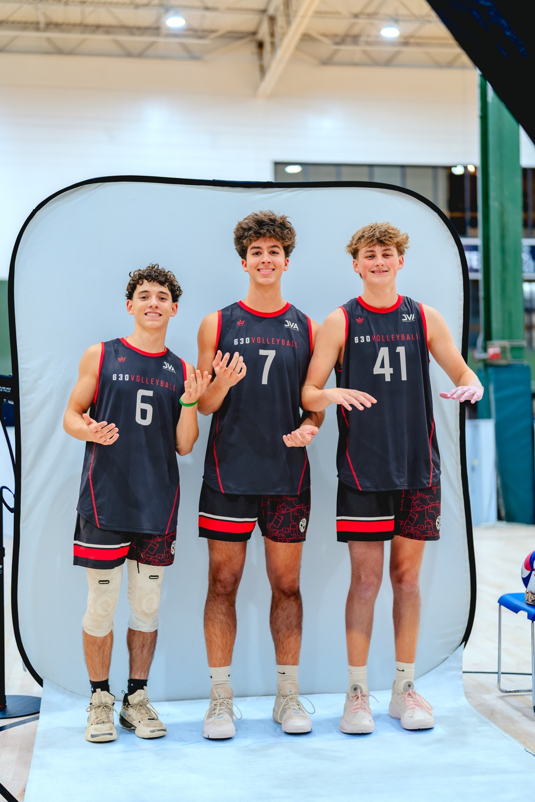 Three players in dark jerseys stand with open hands.
