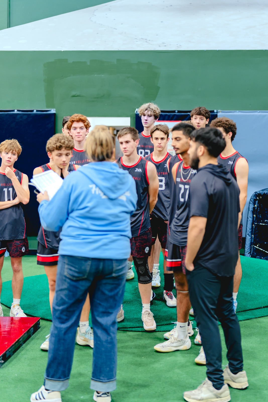 Players in dark jerseys gather around a person in blue holding a sheet.