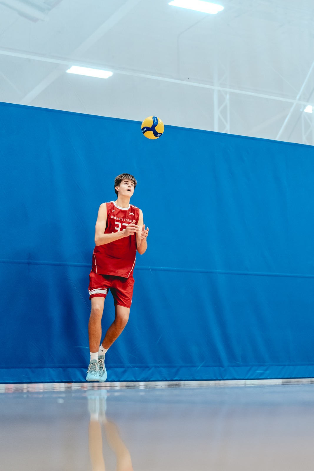 A player in red jumps and looks up at the ball.