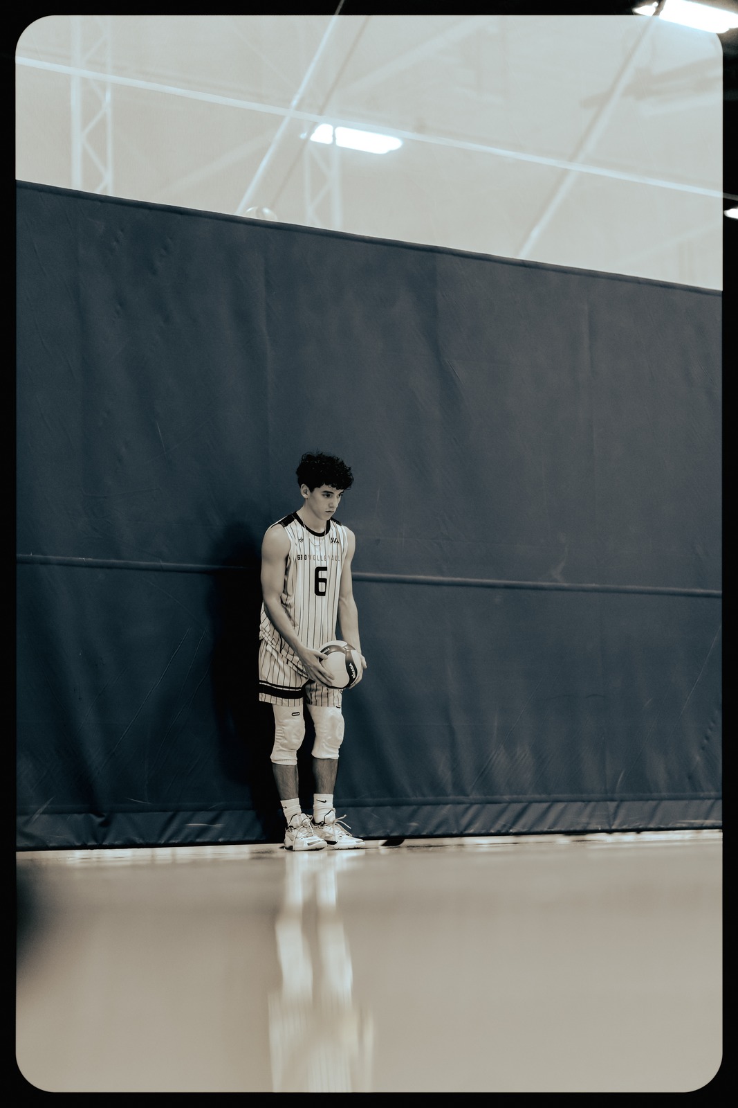 A player in a white and black uniform stands holding a ball.