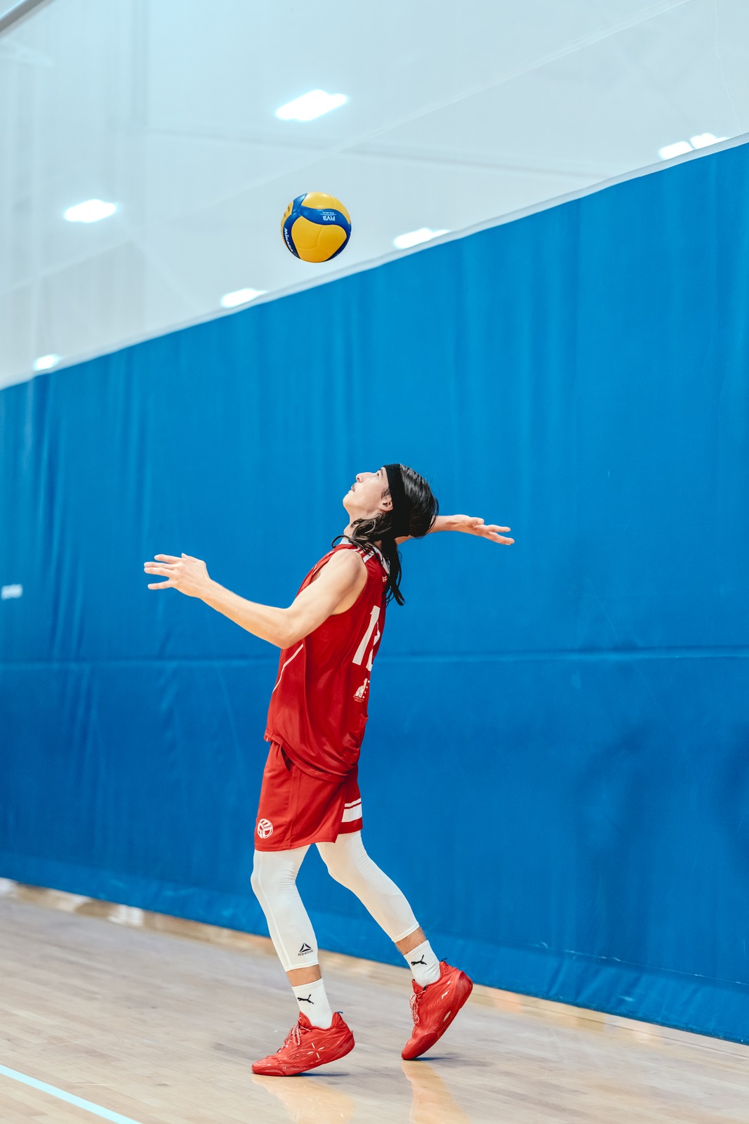 A player in red reaches up towards the ball.