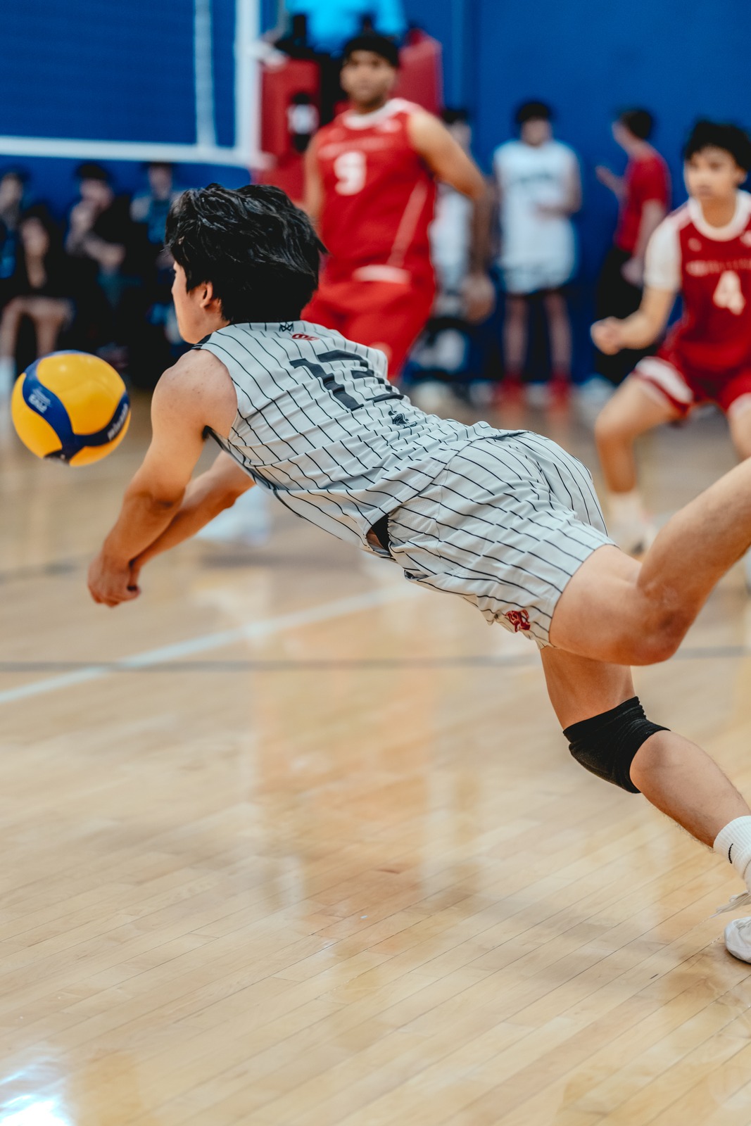 A player in a gray striped top dives low for the ball.